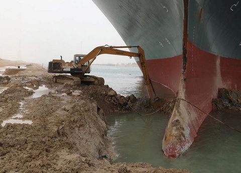 A back hoe on the bank of the Suez, trying to free the Ever Given cargo ship
