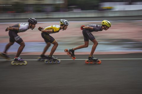 Three roller bladers in racing gear competing, with a blurred background.
